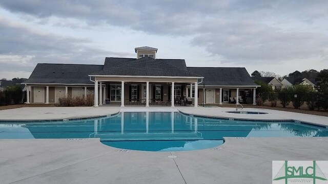 pool with a patio and a hot tub