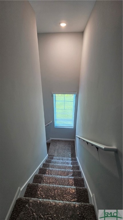 stairway featuring dark carpet