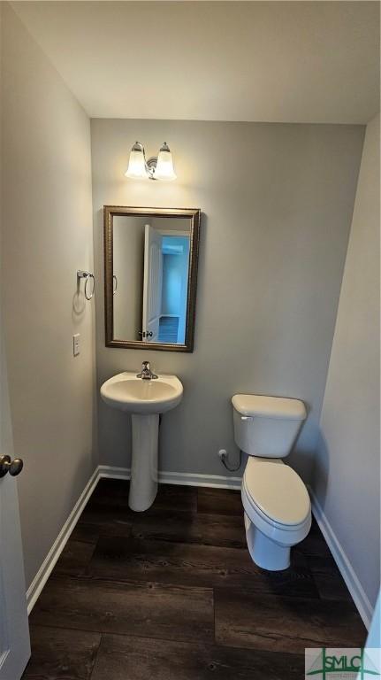 bathroom featuring toilet, wood finished floors, and baseboards