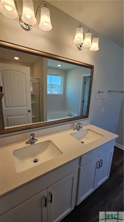 bathroom featuring double vanity, a sink, a stall shower, and wood finished floors