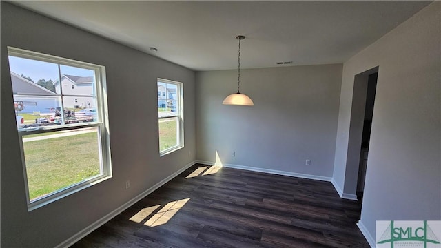 unfurnished dining area featuring dark wood-style flooring, baseboards, and visible vents