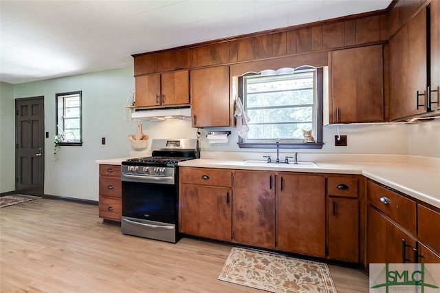 kitchen with sink, stainless steel gas stove, and light wood-type flooring