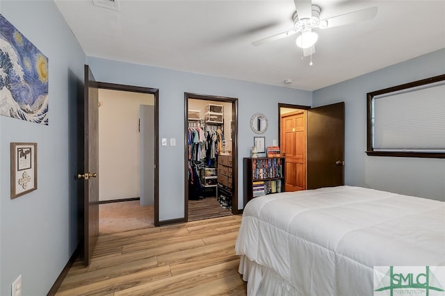 bedroom with a spacious closet, ceiling fan, light hardwood / wood-style floors, and a closet