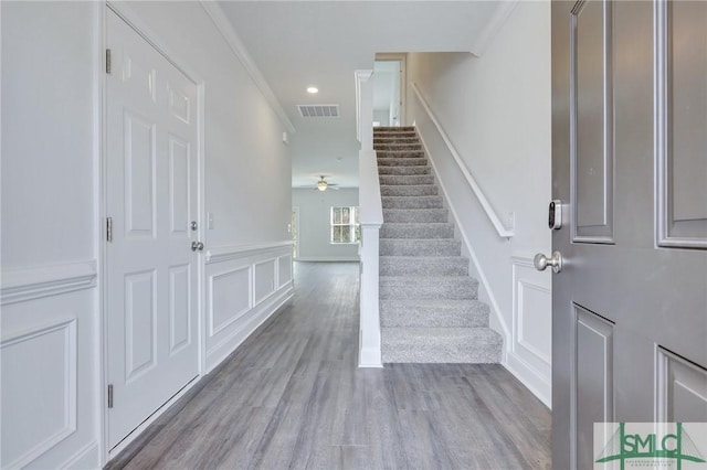 entrance foyer with light hardwood / wood-style flooring, ceiling fan, and ornamental molding