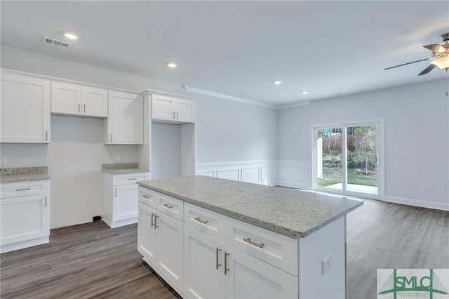 kitchen with white cabinets, light stone countertops, and dark wood-type flooring