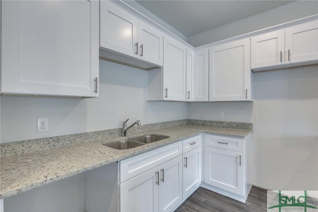 kitchen featuring dark hardwood / wood-style floors, light stone counters, white cabinetry, and sink