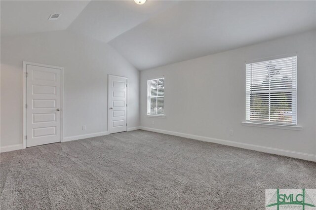 spare room with carpet flooring and vaulted ceiling