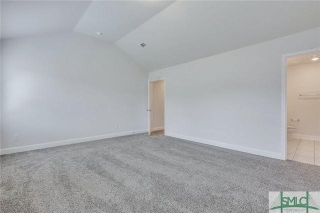 spare room featuring light carpet and lofted ceiling