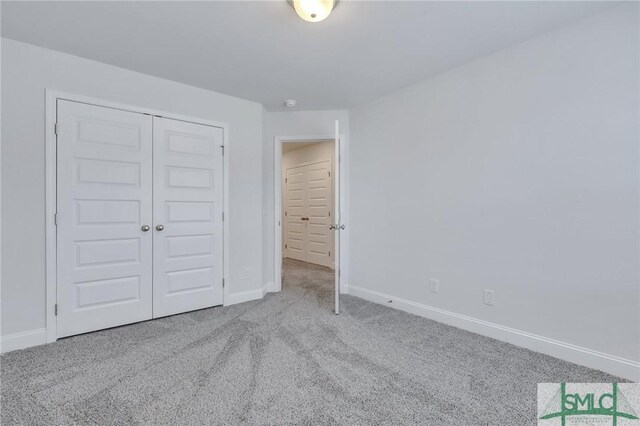 unfurnished bedroom with light colored carpet and a closet