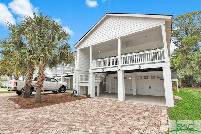 raised beach house with a garage, a balcony, and ceiling fan
