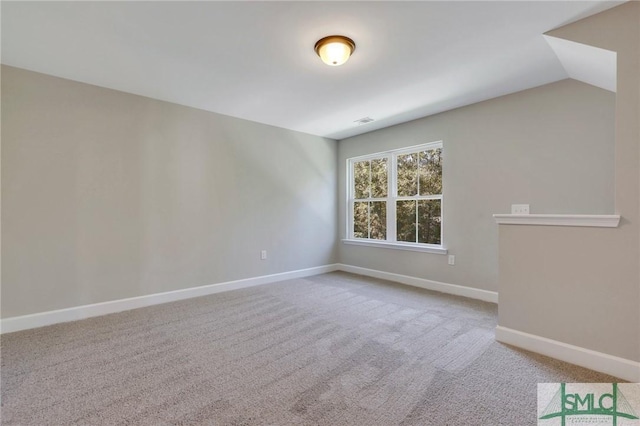 carpeted spare room with vaulted ceiling