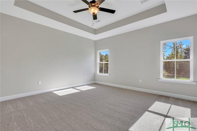 carpeted spare room with ceiling fan and a raised ceiling