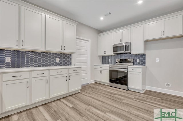 kitchen featuring stainless steel appliances, white cabinetry, light wood-type flooring, and decorative backsplash