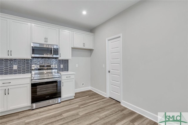 kitchen with appliances with stainless steel finishes, light wood-type flooring, white cabinets, and backsplash