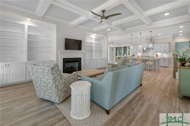 living room featuring light wood-type flooring, ornamental molding, coffered ceiling, ceiling fan with notable chandelier, and beamed ceiling