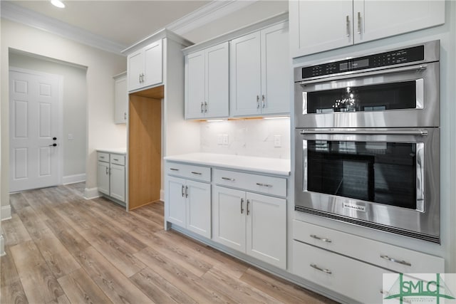 kitchen with white cabinetry, tasteful backsplash, light hardwood / wood-style flooring, double oven, and crown molding