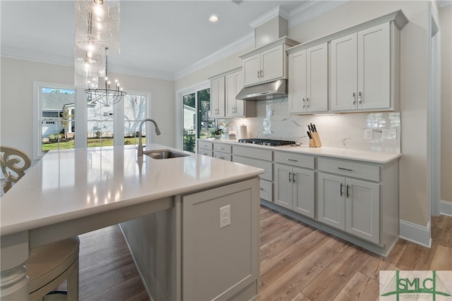 kitchen featuring sink, light hardwood / wood-style flooring, a notable chandelier, decorative light fixtures, and stainless steel gas stovetop