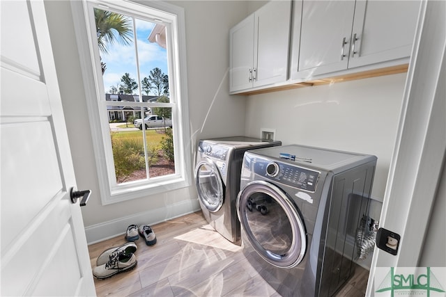 clothes washing area featuring separate washer and dryer, cabinets, a healthy amount of sunlight, and light hardwood / wood-style floors