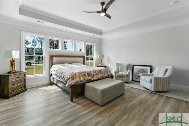 bedroom featuring a tray ceiling, ceiling fan, hardwood / wood-style floors, and crown molding