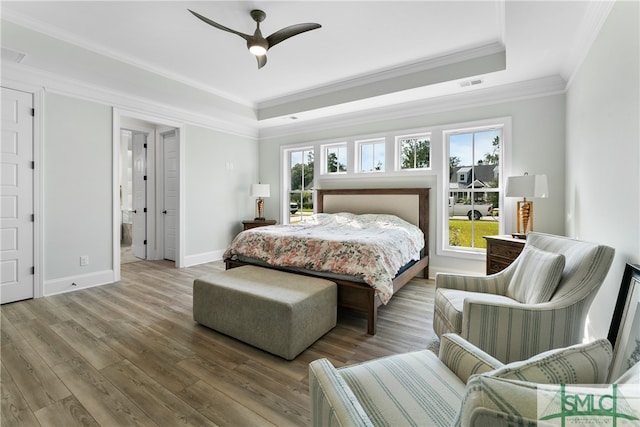 bedroom featuring hardwood / wood-style floors, ceiling fan, a raised ceiling, and ornamental molding