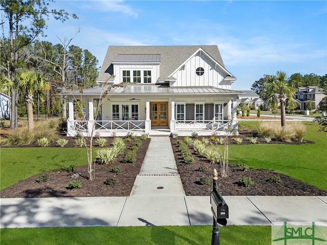 view of front of property featuring french doors, covered porch, and a front yard