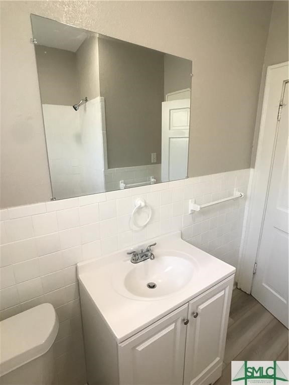 bathroom featuring vanity, hardwood / wood-style flooring, toilet, and tile walls