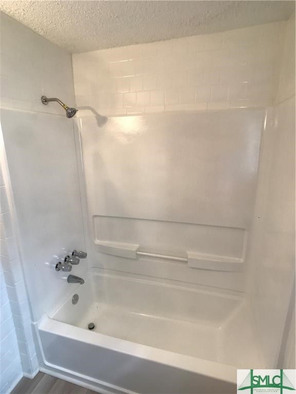 bathroom with shower / bathtub combination and a textured ceiling