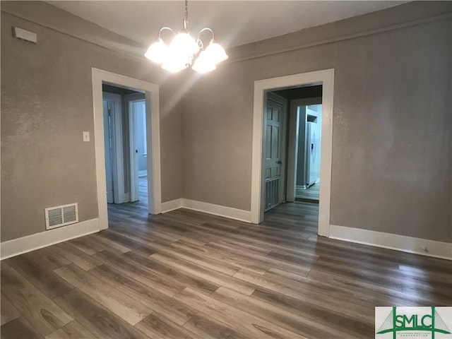 empty room with a notable chandelier and hardwood / wood-style floors