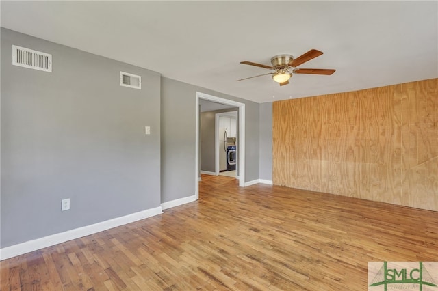 spare room featuring wooden walls, light wood-type flooring, and ceiling fan