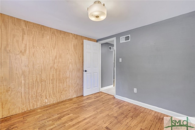 unfurnished room with wooden walls and wood-type flooring