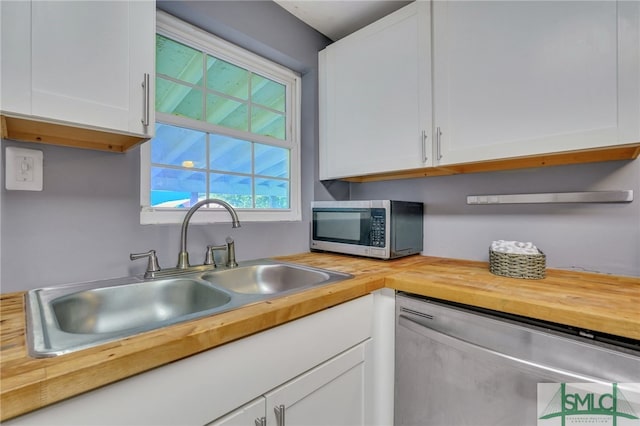 kitchen with appliances with stainless steel finishes, sink, and white cabinets