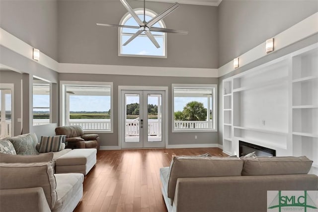 living room with baseboards, a glass covered fireplace, wood finished floors, french doors, and built in shelves