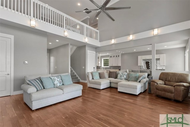 living room with stairs, ceiling fan, wood finished floors, and baseboards