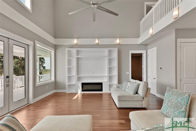 living area with french doors, a fireplace, baseboards, and wood finished floors