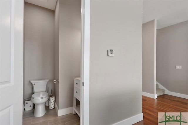 bathroom with baseboards, toilet, and wood finished floors