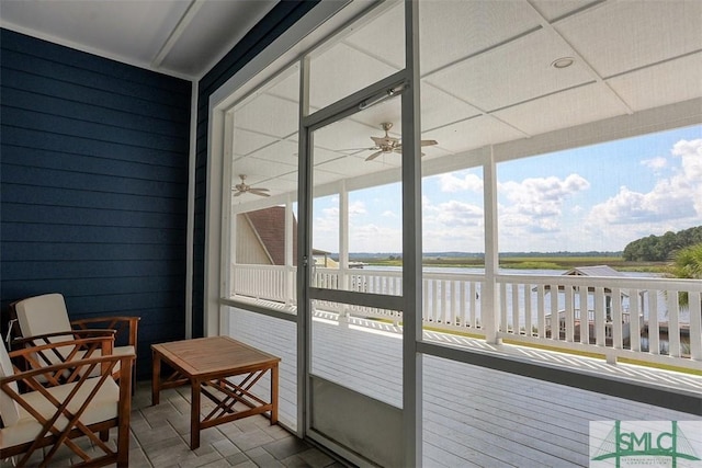 sunroom featuring ceiling fan and a water view