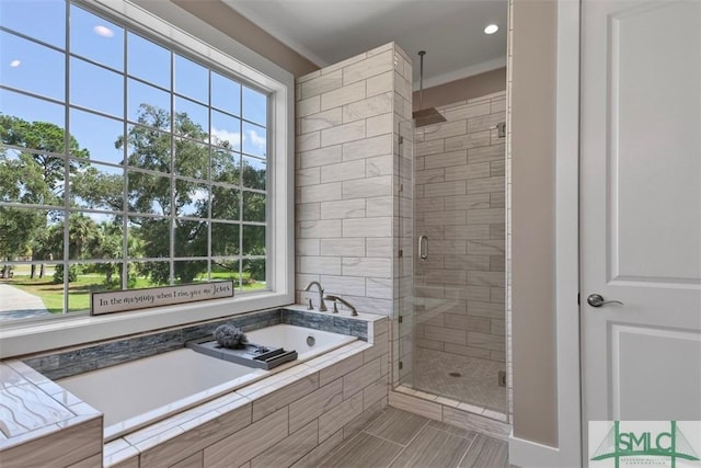 bathroom featuring a garden tub, a shower stall, and crown molding