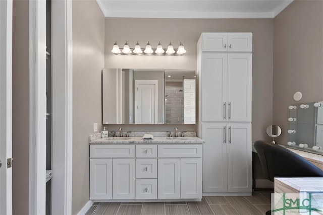 bathroom with a tile shower, double vanity, ornamental molding, and a sink