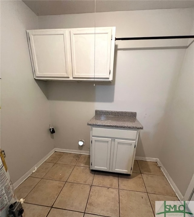 clothes washing area featuring light tile patterned flooring and cabinets