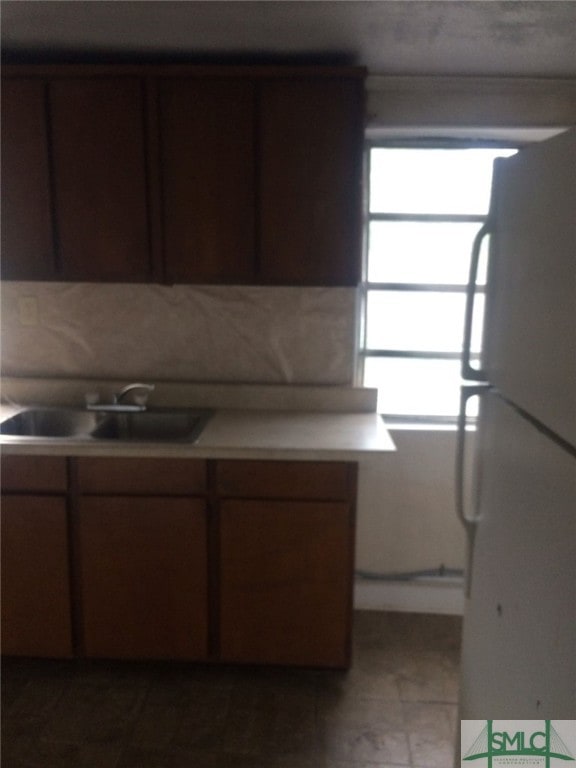 kitchen featuring plenty of natural light, sink, white fridge, and tile patterned flooring