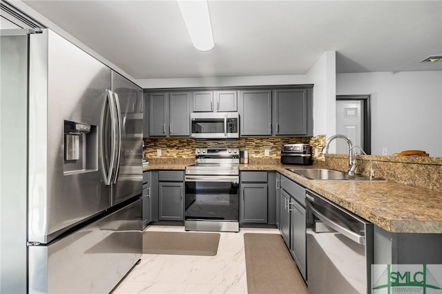 kitchen featuring appliances with stainless steel finishes, tasteful backsplash, sink, gray cabinetry, and kitchen peninsula