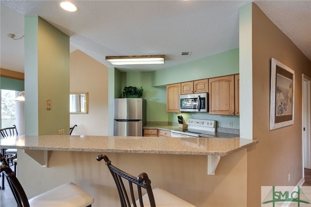 kitchen featuring appliances with stainless steel finishes, a breakfast bar area, and kitchen peninsula