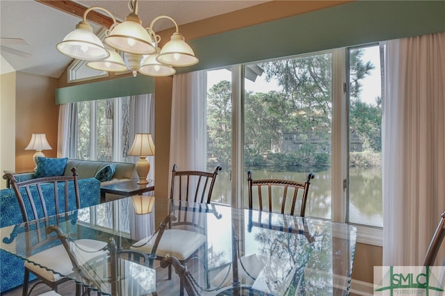 dining area featuring a notable chandelier, lofted ceiling, and a water view