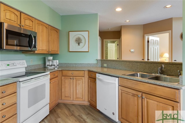 kitchen with kitchen peninsula, light hardwood / wood-style flooring, white appliances, and sink