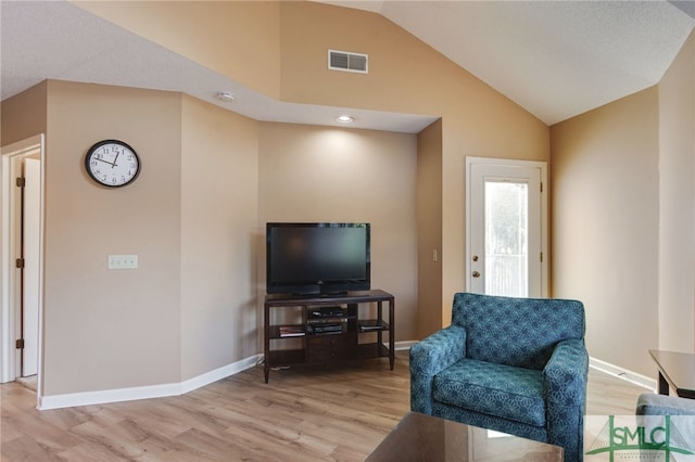 living room featuring lofted ceiling and light hardwood / wood-style floors