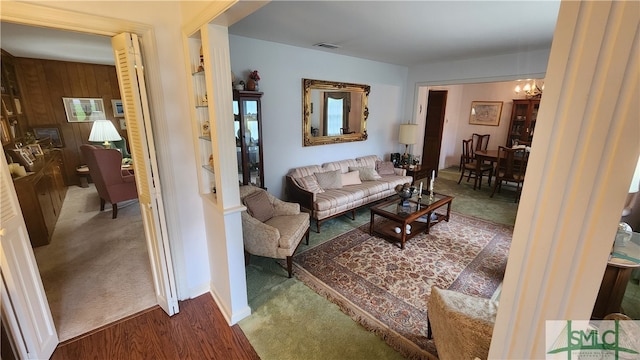 living room featuring a notable chandelier, wood walls, and carpet floors