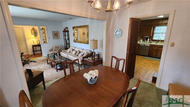 dining area featuring light wood-type flooring, sink, and an inviting chandelier