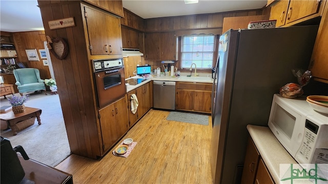 kitchen featuring light carpet, fridge, stainless steel dishwasher, wall oven, and sink