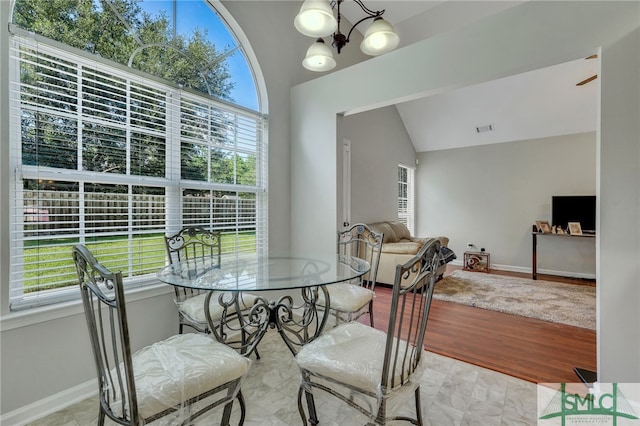 dining area with light hardwood / wood-style flooring, lofted ceiling, and an inviting chandelier