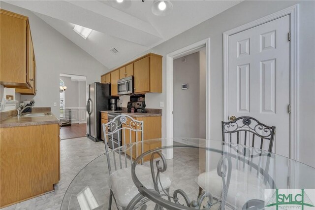 kitchen with light hardwood / wood-style flooring, lofted ceiling with skylight, stainless steel appliances, and sink